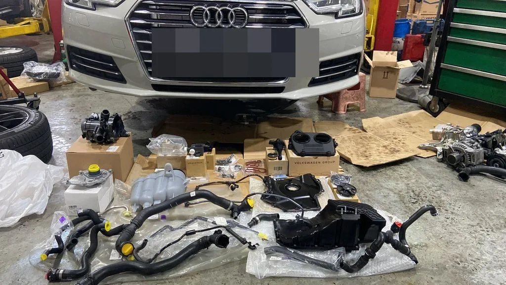 Replacement coolant and oil leak parts laid out in front of an Audi A4 at our Singapore workshop
