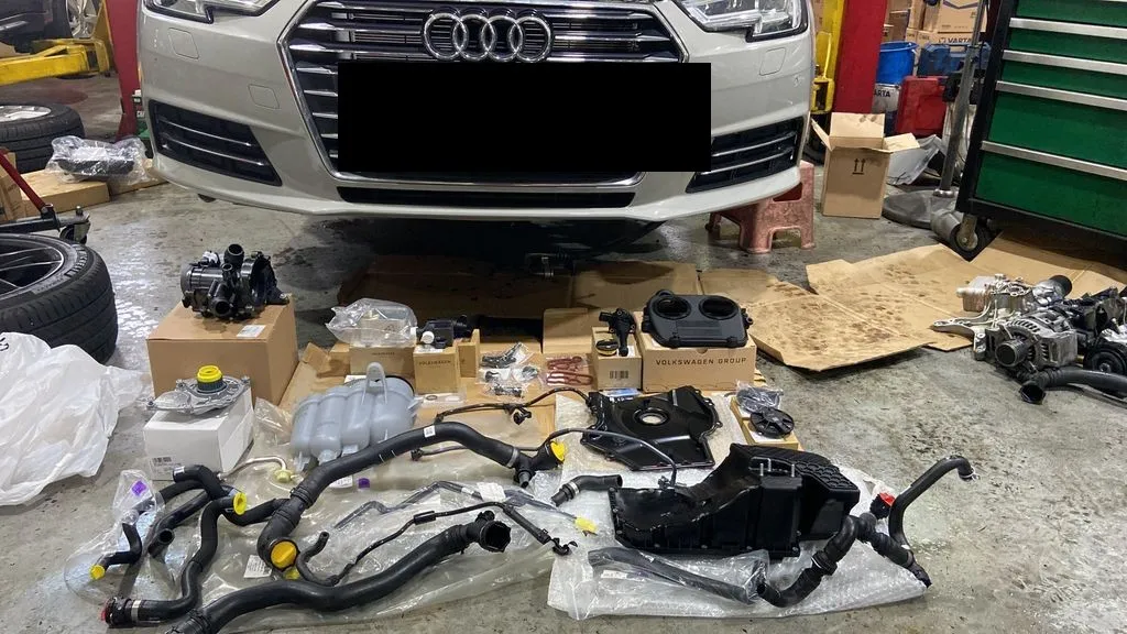 Genuine replacement coolant and oil leak parts laid out in front of an Audi A4 at our Singapore workshop
