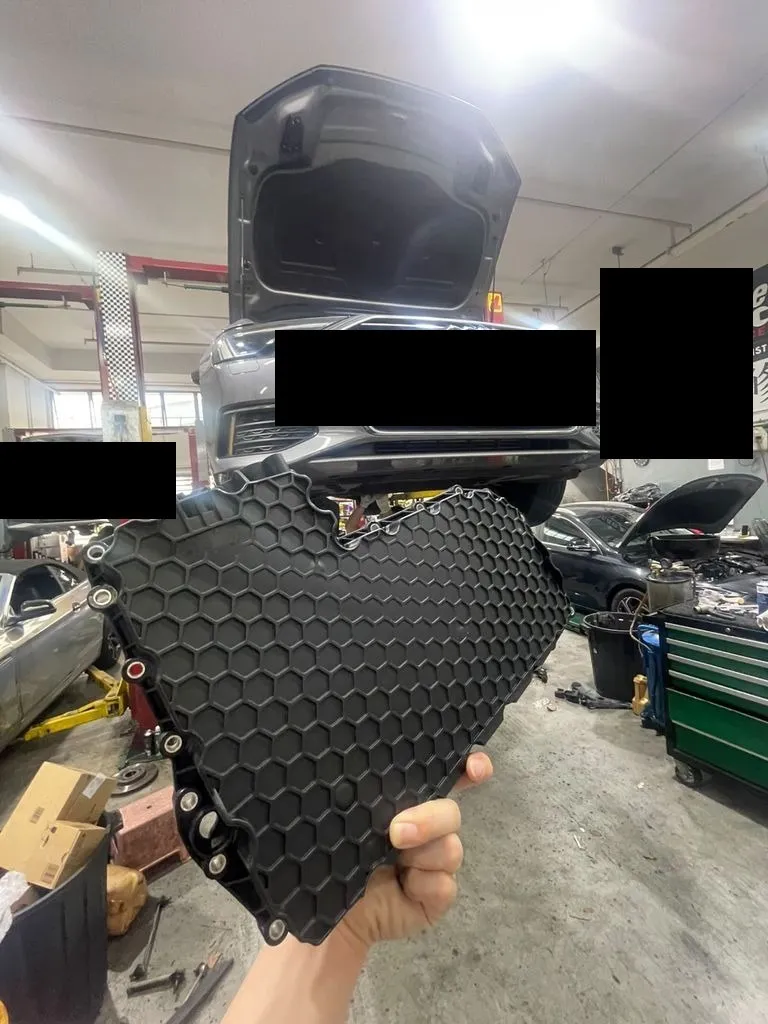 Audi A6 gearbox oil sump pan held up in front of the car at our Singapore workshop