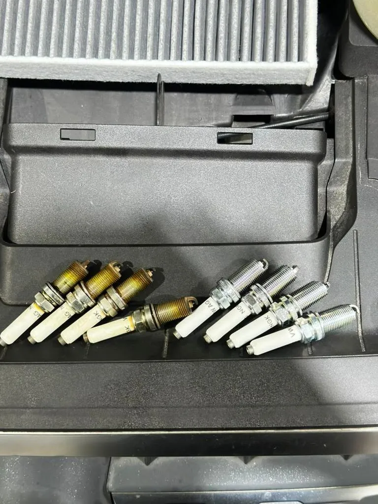 Side-by-side comparison of worn Audi Q7 TFSI spark plugs (left) and new replacement plugs (right)