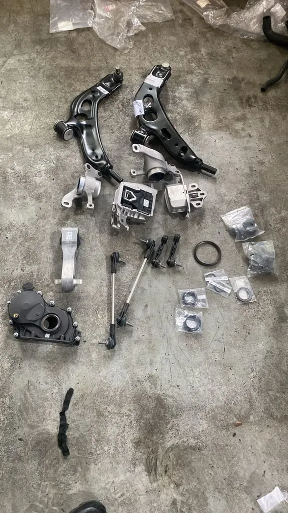 New BMW 216 front lower arms, engine and gearbox mounts, timing cover, linkages and oil seals laid out before fitting