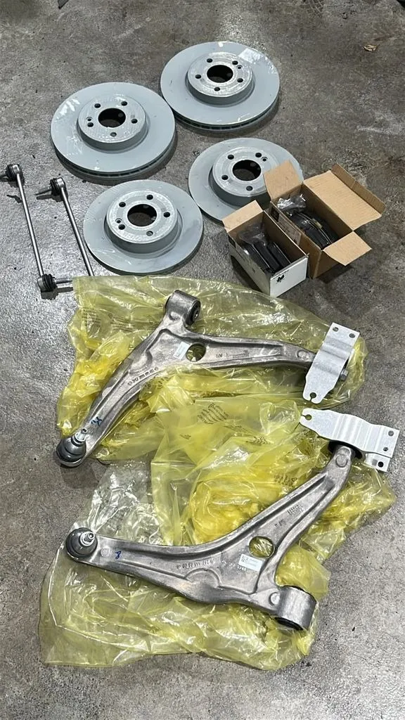 New BMW 3 Series brake discs and front lower control arms laid out for a full brake and suspension repair at our Singapore workshop