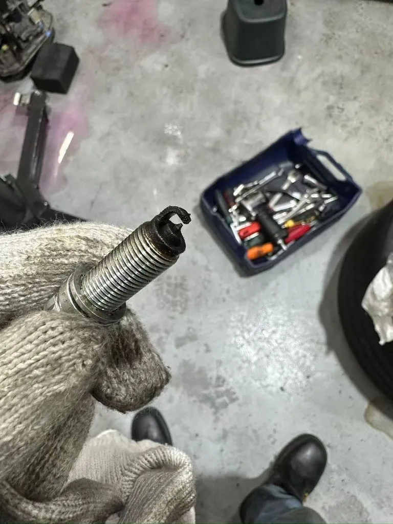 Severely burnt BMW spark plug with the electrode destroyed, removed from the G30 5 Series during inspection