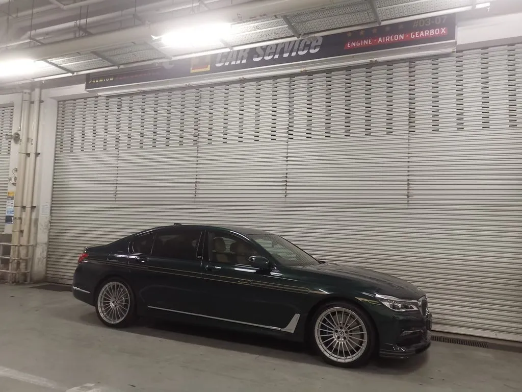 British Racing Green BMW Alpina B7 with gold coach pinstripes parked outside 1 Car Service workshop in Singapore