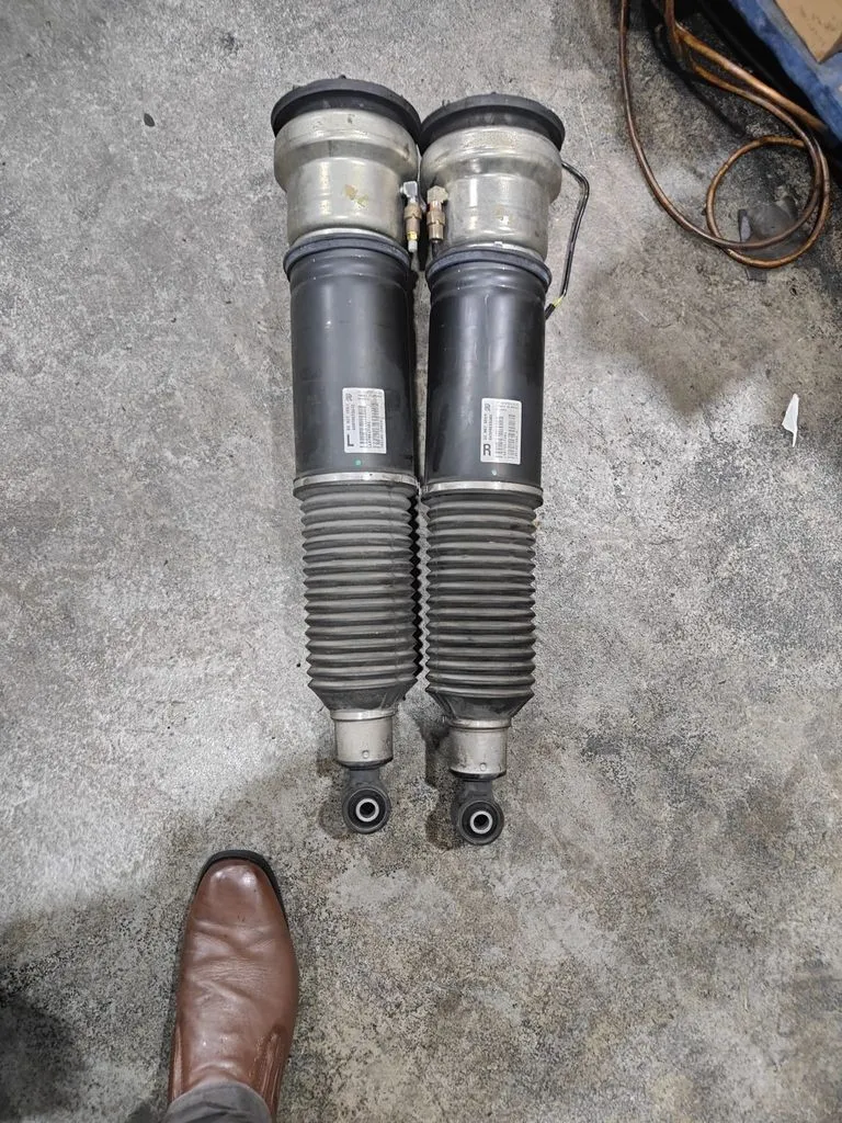 Old BMW Alpina B7 air suspension struts removed from the car and laid out on the workshop floor