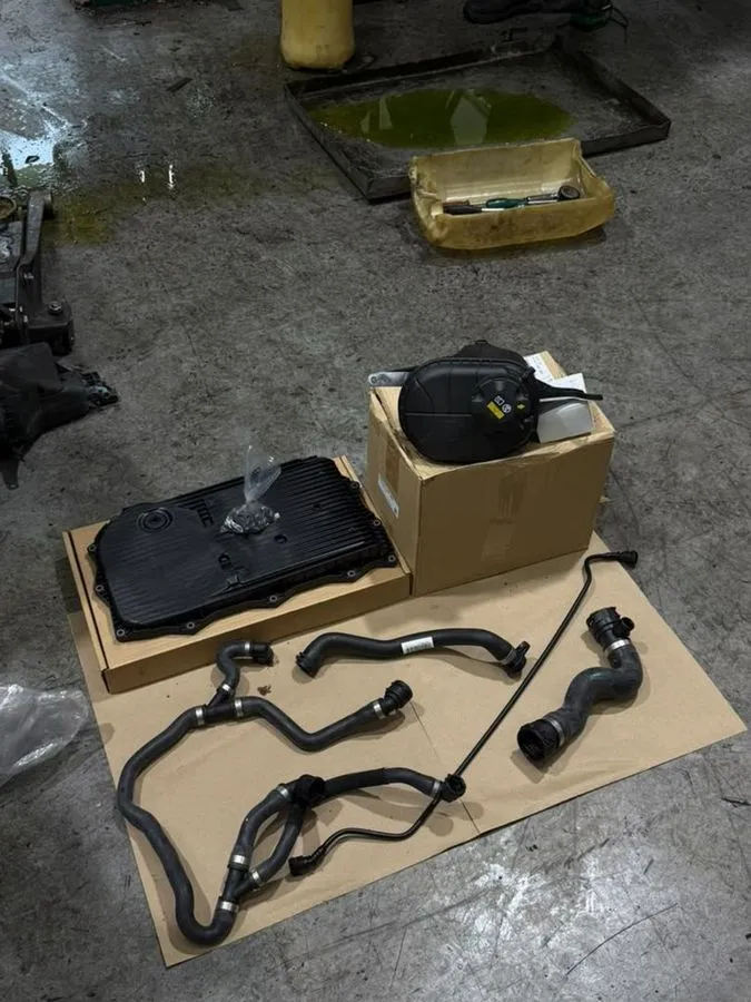New BMW coolant hoses, expansion tank and automatic gearbox pan laid out before fitting