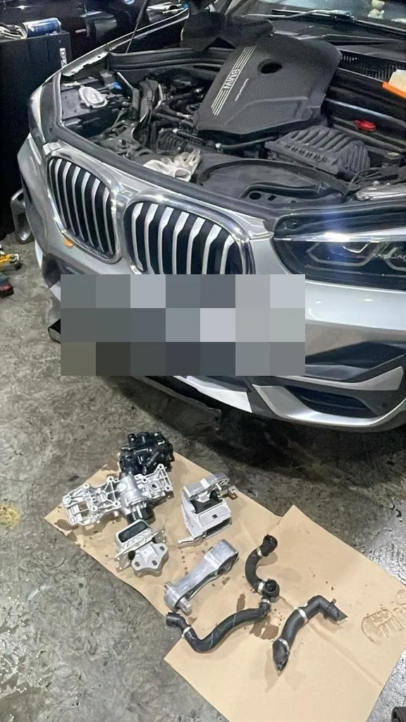 BMW X1 coolant system parts including thermostat and water pump laid out for replacement at our Singapore workshop