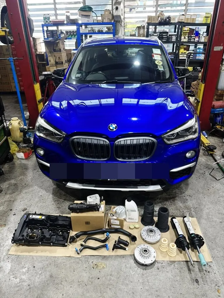 Blue BMW X1 at our Singapore workshop with all replacement parts laid out in front of the car before the comprehensive repair