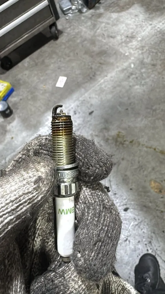 Worn BMW spark plug removed from the X1 during the high-mileage inspection