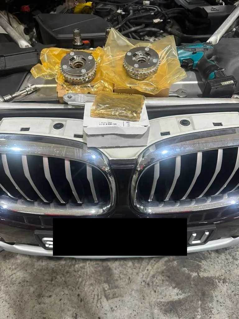 BMW X4 with hood open and new timing components laid out on the engine bay at our Singapore workshop, plate censored