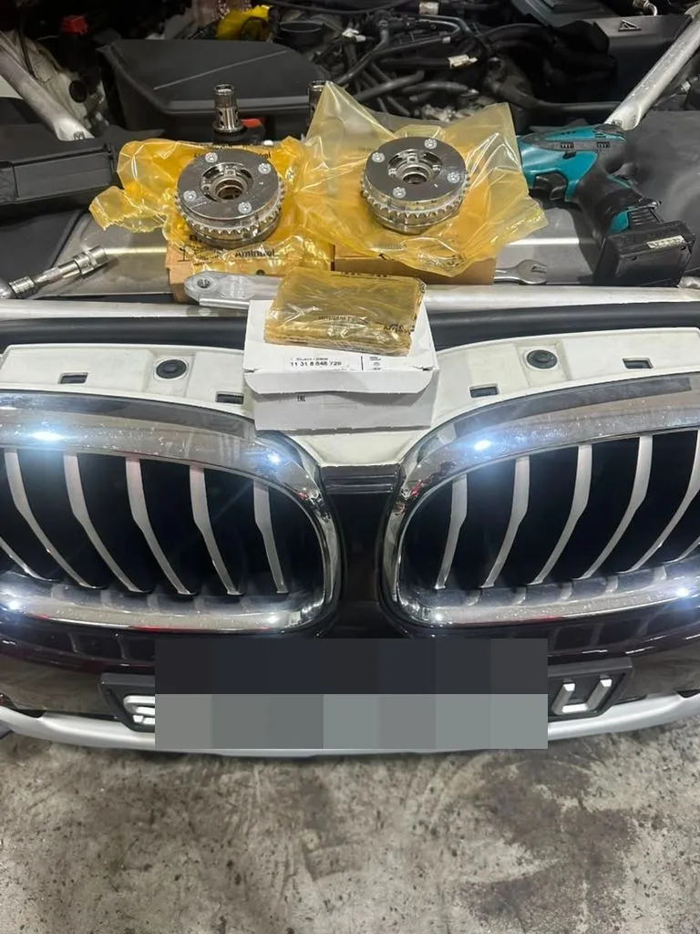 BMW X4 with hood open and new timing components laid out on the engine bay at our Singapore workshop, plate censored