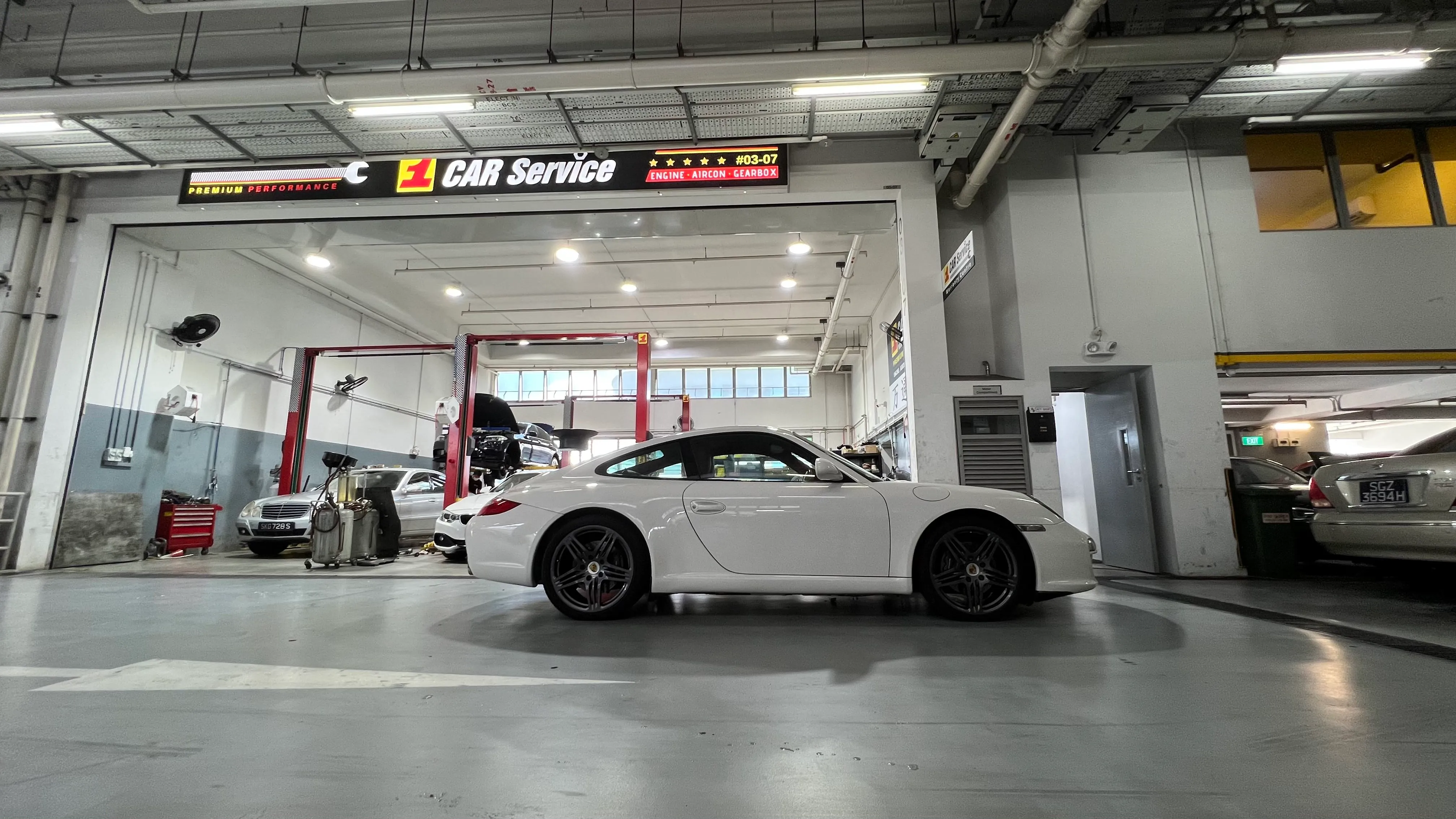 A white Porsche 911 in our Singapore service bay, with other continental cars on the lifts behind
