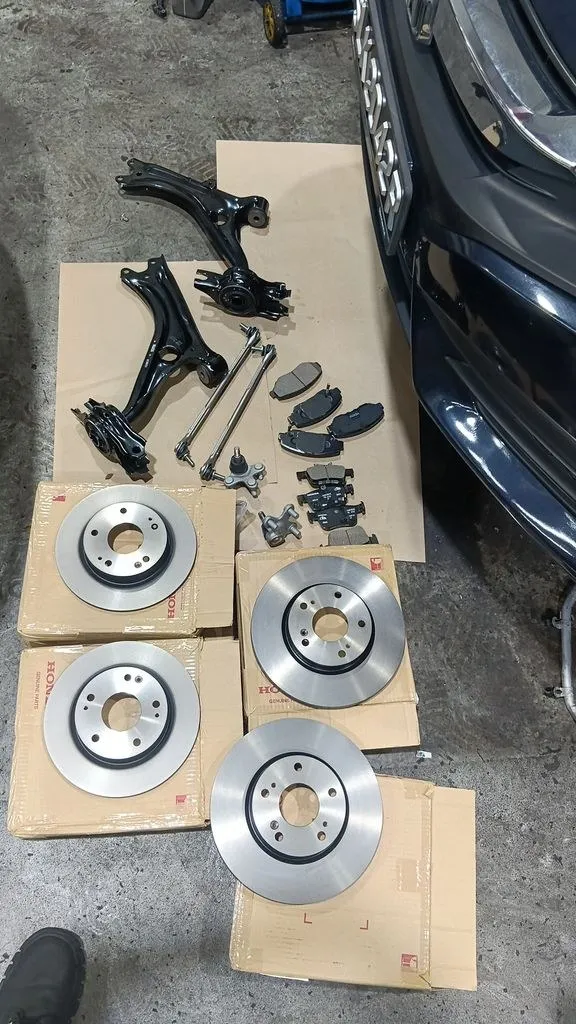 Honda genuine brake discs with new lower arms, linkages and brake pads laid out at 1 Car Service Singapore workshop
