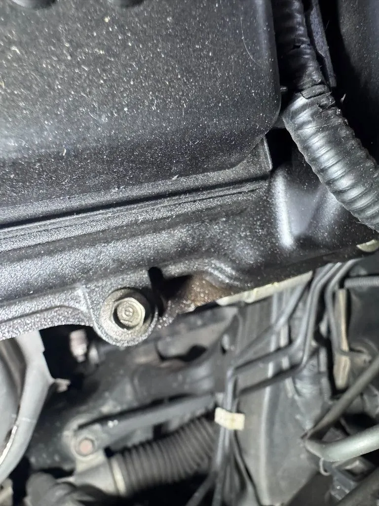 Engine bay inspection locating the valve cover oil leak on a Honda