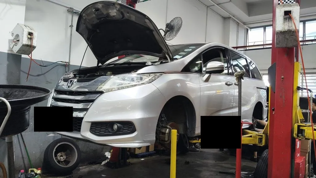 Car on the lift with the wheel off for brake pad and disc replacement at our Singapore workshop