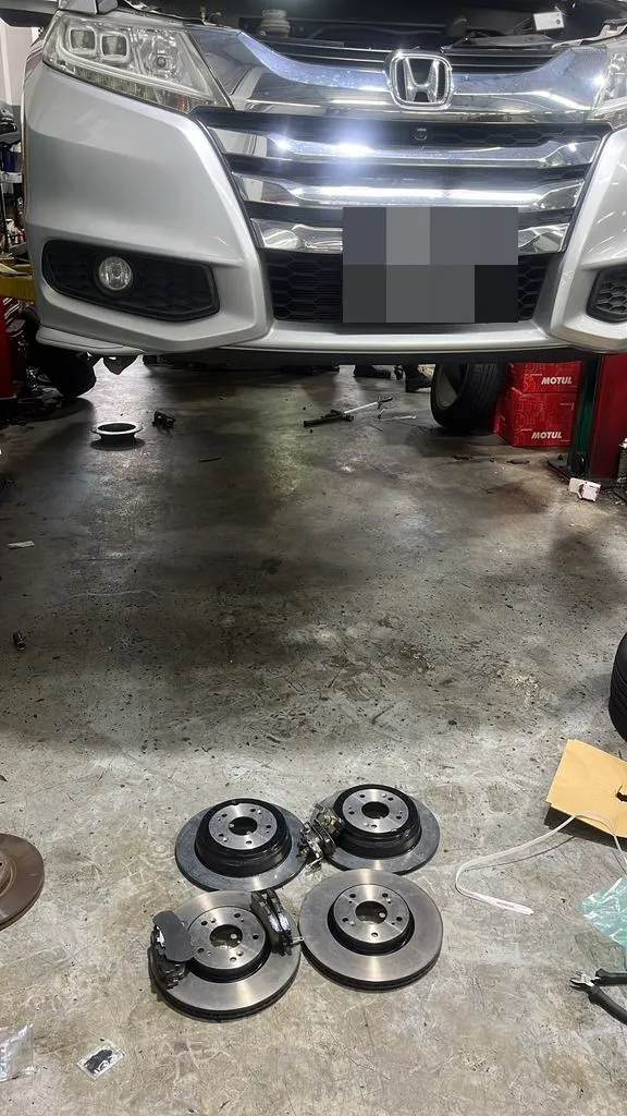 Silver Honda Odyssey with its four new brake discs and pads ready to fit at our Singapore workshop