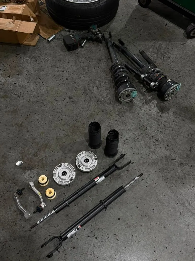 Old worn shock absorber next to its new replacement during suspension repair at our Singapore workshop