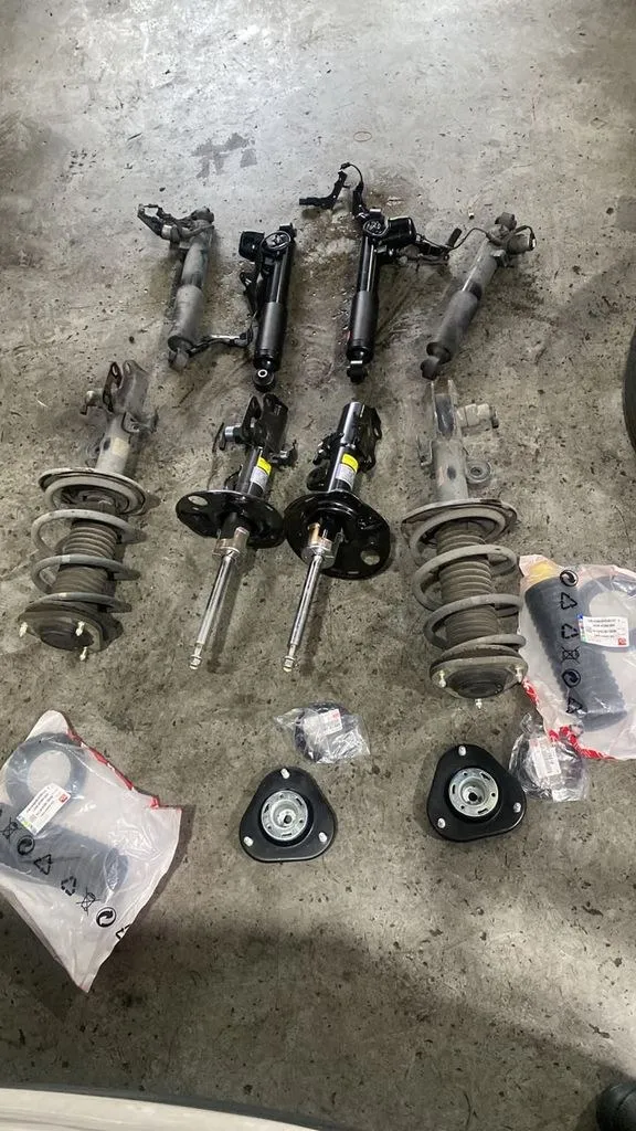 All four removed Lexus IS F-Sport AVS strut assemblies laid out at 1 Car Service Singapore, with two new strut top mounts in packaging