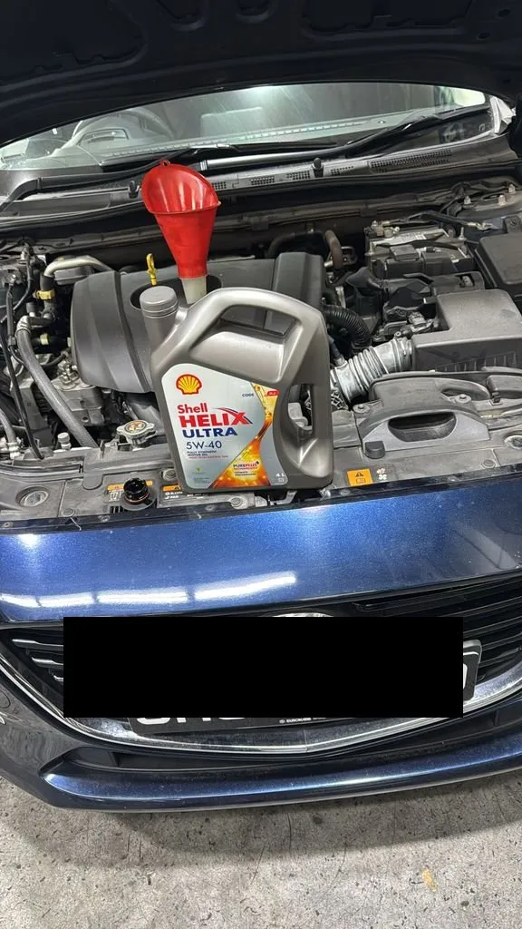 Mazda on a lift at our Singapore workshop with fan belt and rear absorber replacement work in progress, plate censored