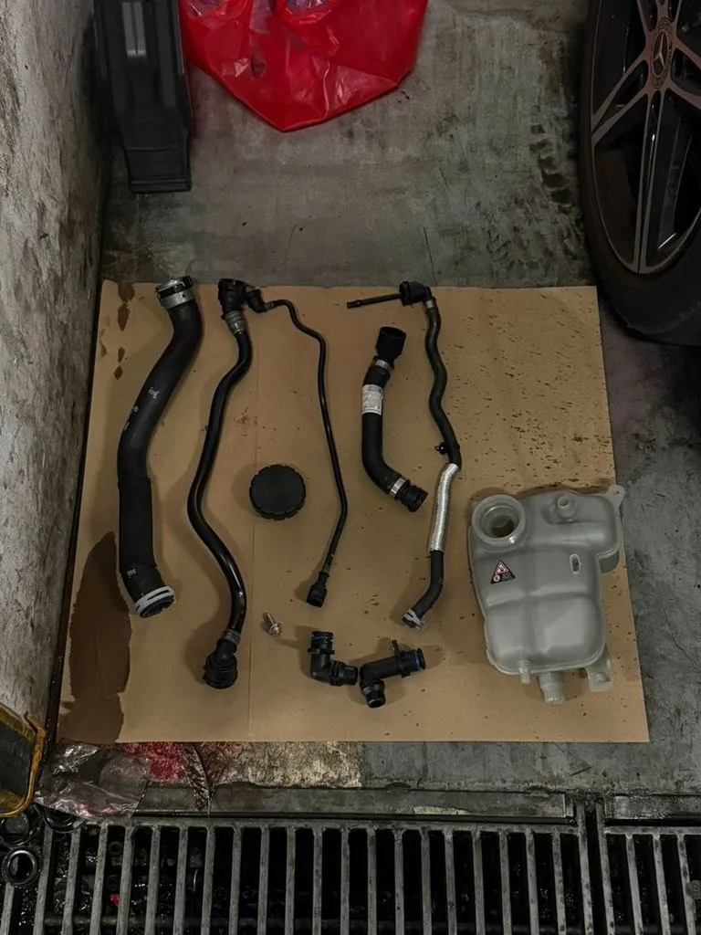 Old coolant hoses and expansion tank removed from a Mercedes-Benz during repair