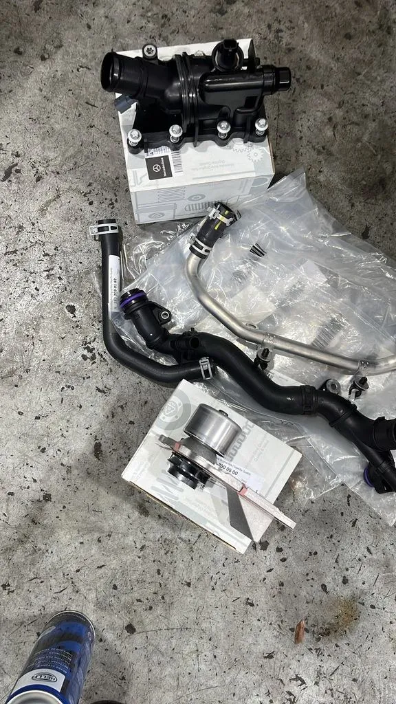 New Mercedes-Benz coolant system parts including thermostat and water pump laid out at 1 Car Service Singapore