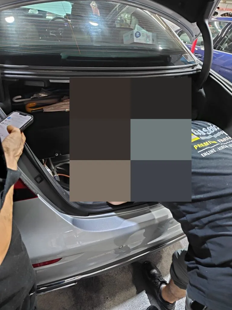 Our team at work in the boot of the silver E350e, with orange high-voltage cabling in view