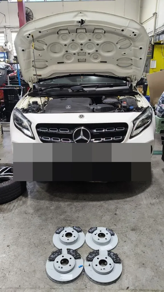 White Mercedes-Benz GLA 200 in our Singapore workshop with new brake discs and pads laid out in front of the car
