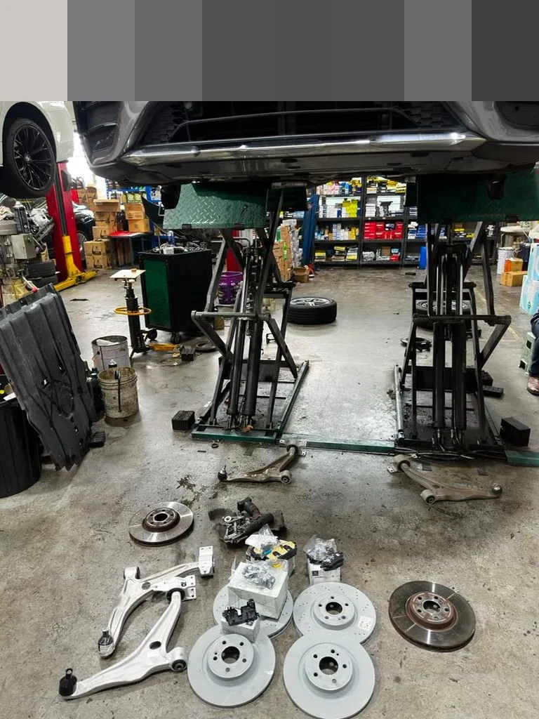 Mercedes GLC on workshop ramps with new front lower arms and brake parts laid out ready to fit, plate censored, at our Singapore workshop