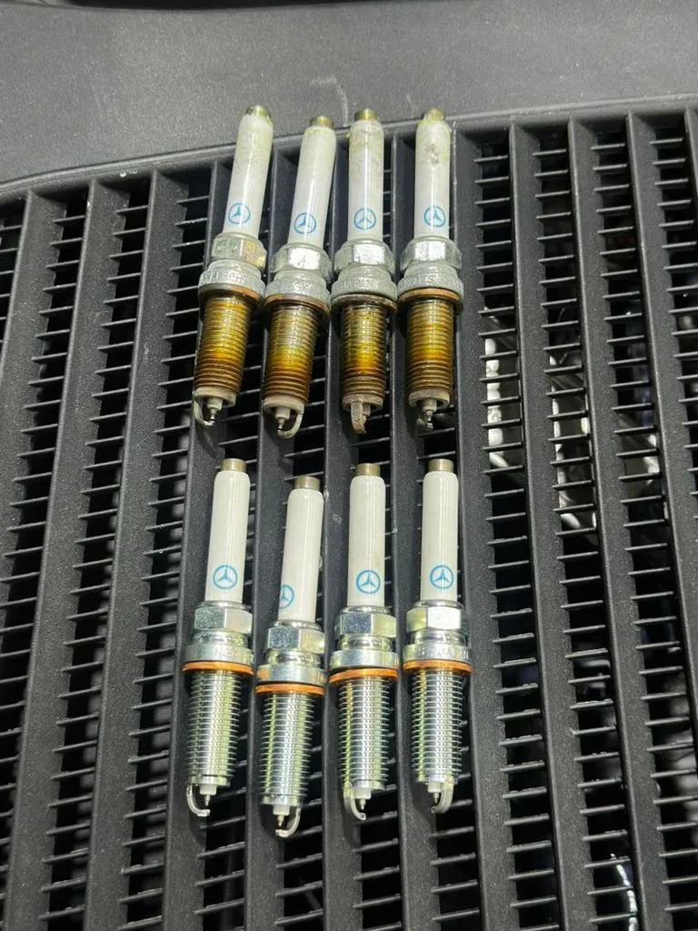 Four Mercedes spark plugs, worn on the left and new Mercedes-spec replacements on the right, from a GLC service in Singapore