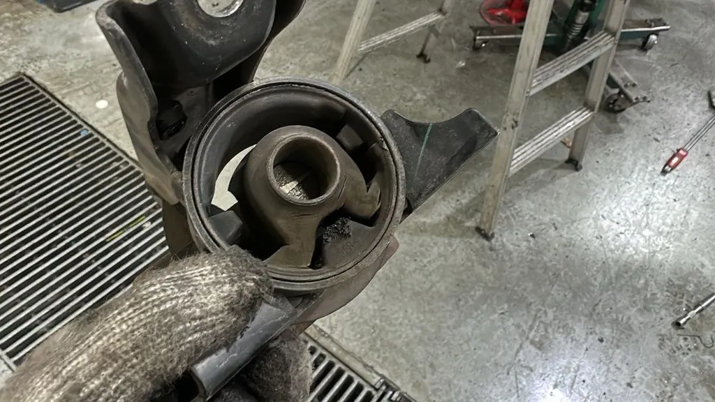Collapsed engine mount rubber from a Mitsubishi Attrage held up at 1 Car Service Singapore workshop showing complete rubber failure