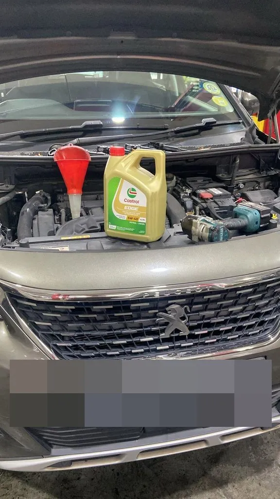 Castrol Edge engine oil and funnel in the engine bay of a Peugeot 5008 during servicing at our Singapore workshop