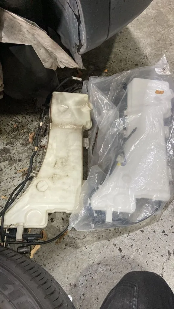 Old Peugeot 5008 windscreen washer tank next to the new tank with motor at our Singapore workshop