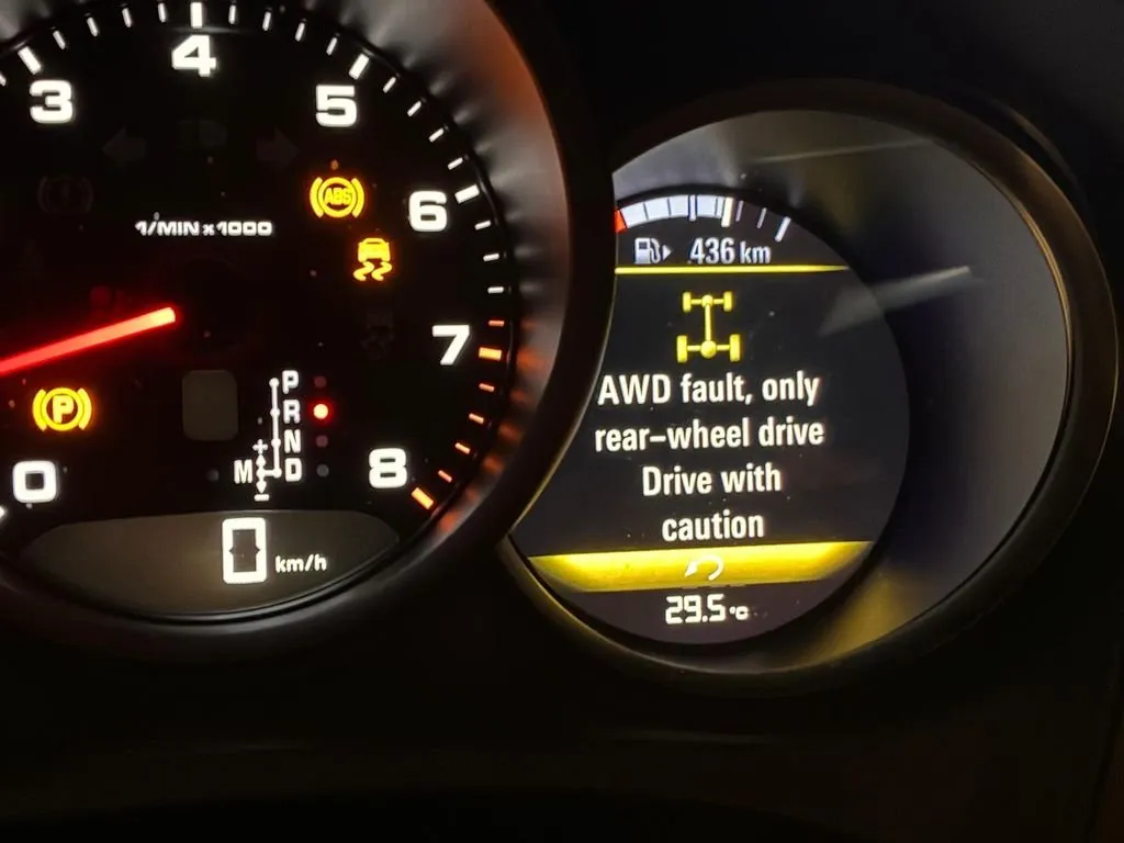 Porsche Macan dashboard showing AWD fault warning and ABS light on, with message advising rear-wheel drive only
