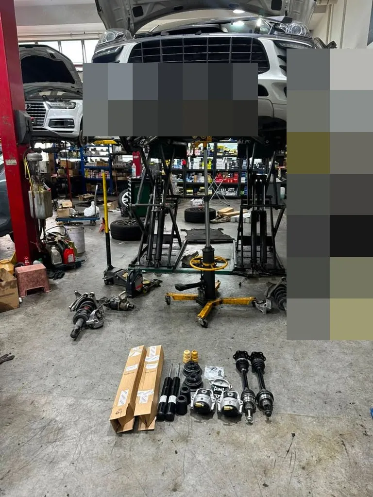 Porsche Macan on a lift at our Singapore workshop with driveshafts, absorbers and engine mount parts laid out for replacement