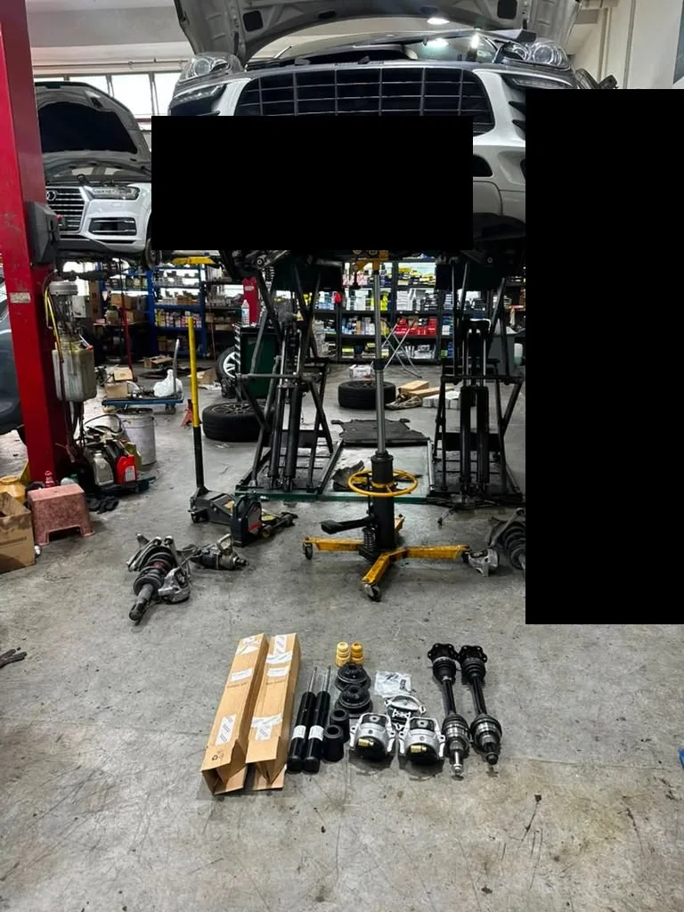 Porsche Macan on a lift at our Singapore workshop with driveshafts, absorbers and engine mount parts laid out for replacement