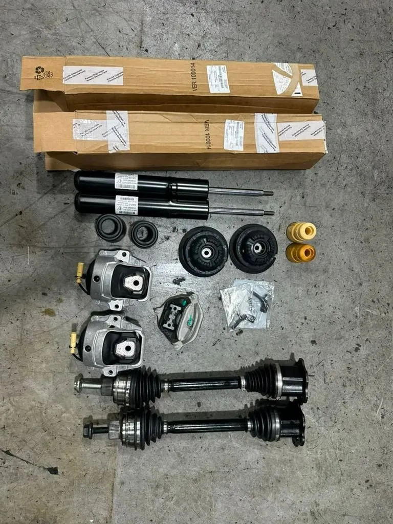 New Porsche Macan absorbers, CV joint shafts and engine mount parts laid out ready for installation