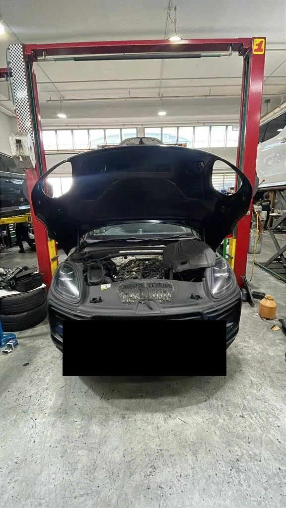 Dark blue Porsche Macan on a workshop lift with the bonnet open at 1 Car Service Singapore