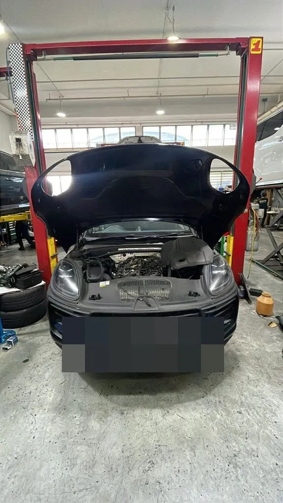 Dark blue Porsche Macan on a workshop lift with the bonnet open at 1 Car Service Singapore