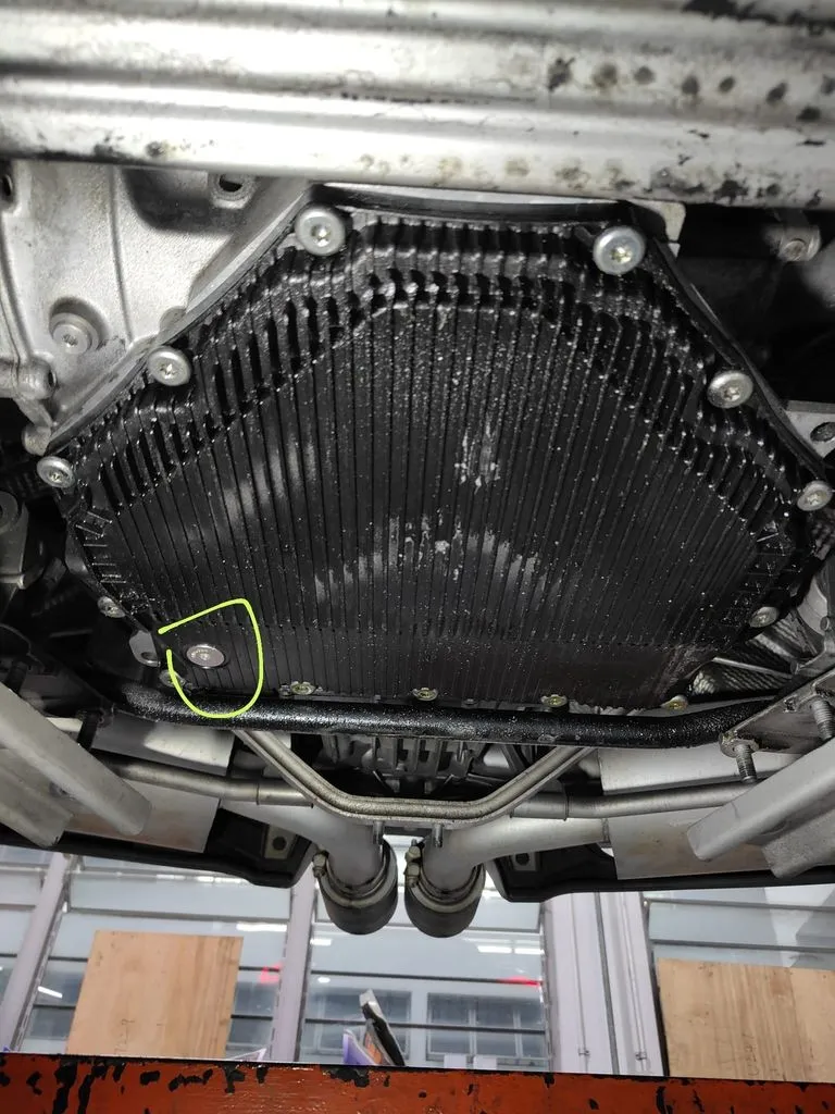 Underside of a Porsche PDK gearbox showing the worn oil pan leaking transmission oil