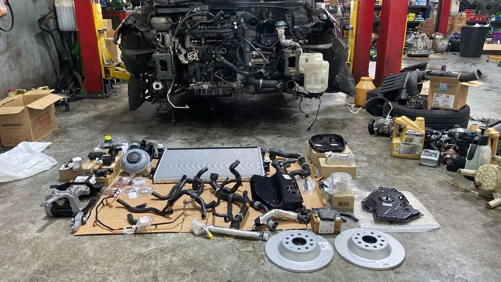 Skoda Octavia cooling system parts laid out at 1 Car Service Singapore workshop, showing radiator, hoses, brake rotors and timing components