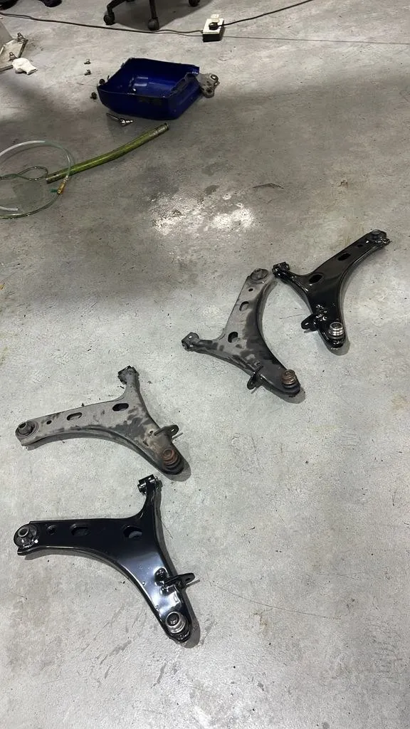 New original Subaru Forester front lower arms with ball joints next to the worn parts removed during the repair