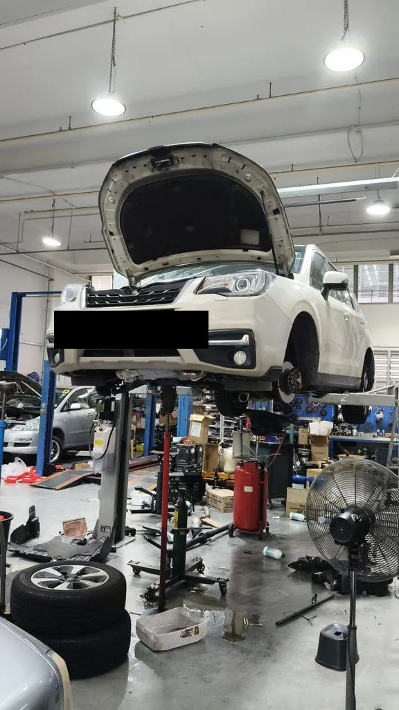 White Subaru Forester on the hoist at our Singapore workshop for a front lower arm and suspension repair