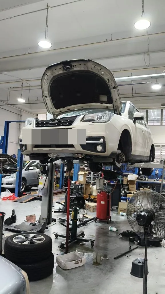 White Subaru Forester on the hoist at our Singapore workshop for a front lower arm and suspension repair