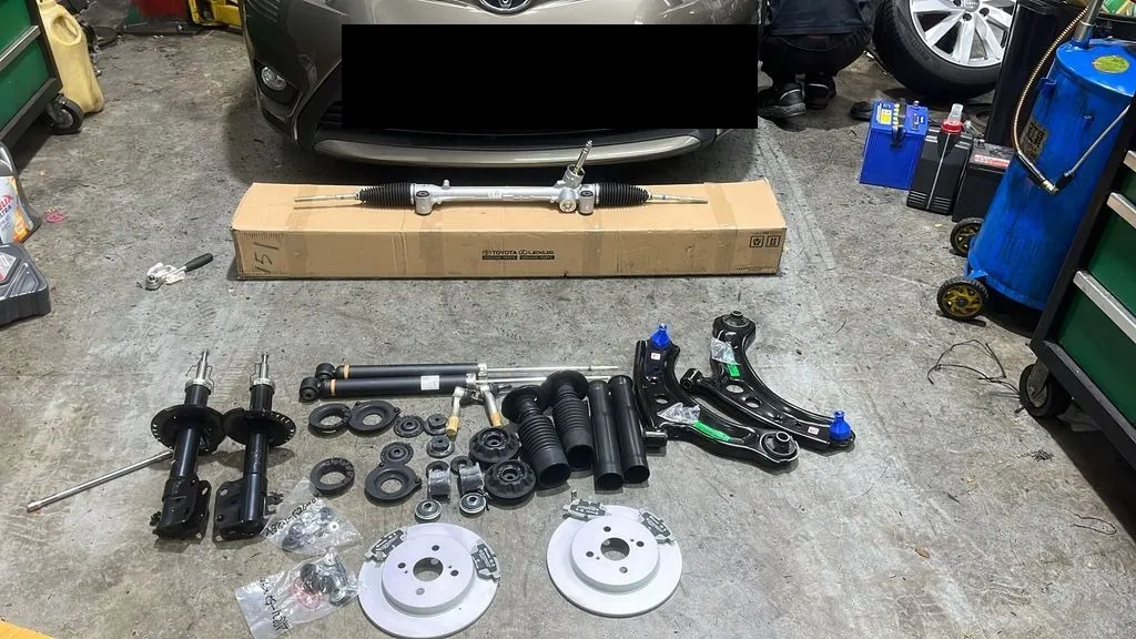 Full set of new Toyota Vios steering rack, absorbers, lower arms and rear brake parts in front of the car at our workshop