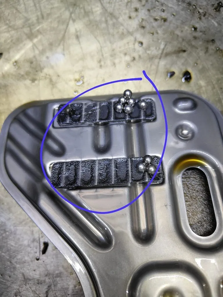 Magnetic sump plug from the VW Golf GTI manual gearbox with steel bearing balls and metallic paste collected on it, confirming bearing failure