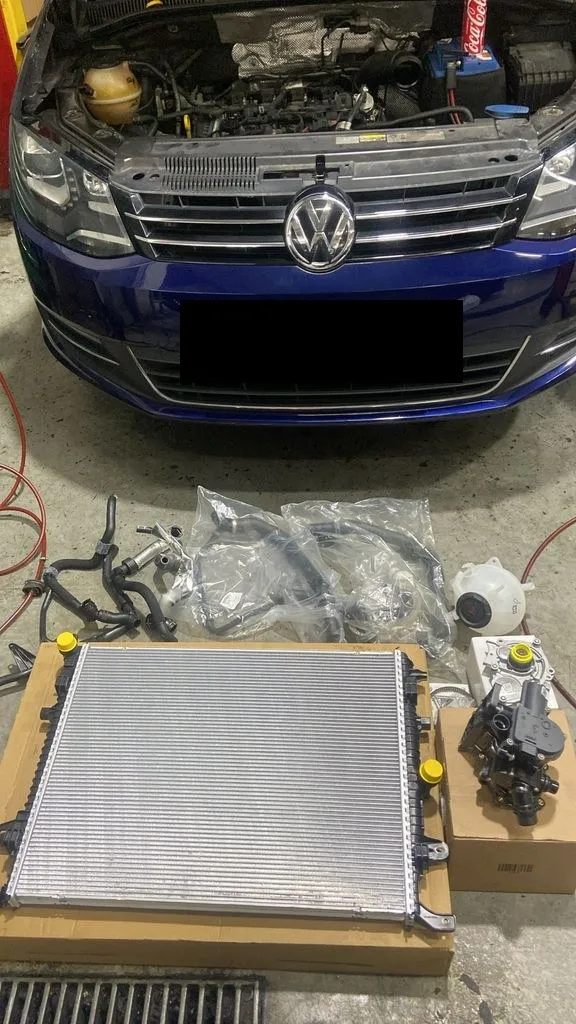 Blue Volkswagen Sharan at our Singapore workshop with a new radiator and coolant hoses laid out for a cooling system repair