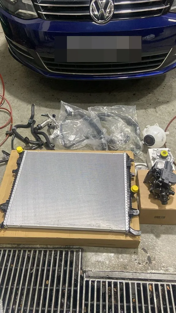 New original Volkswagen radiator, coolant hoses, expansion tank and water pump ready to fit during a cooling system repair in Singapore