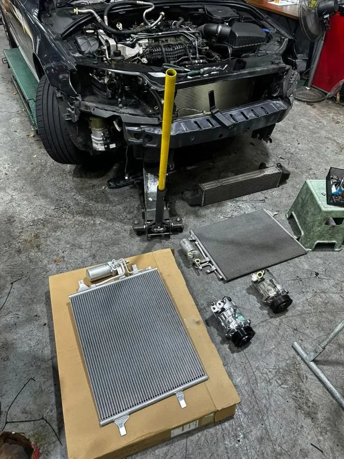 New Volvo S80 AC condenser in packaging alongside the new compressor and old condenser, ready for fitting in the workshop