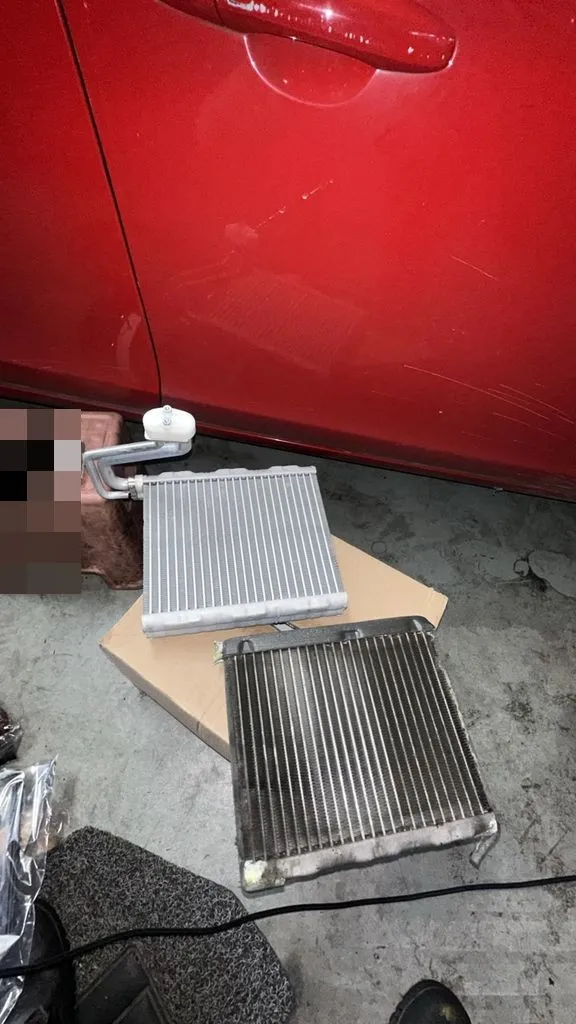 Old darkened evaporator cooling coil next to a new clean coil from a Volvo V60 aircon repair at our Singapore workshop