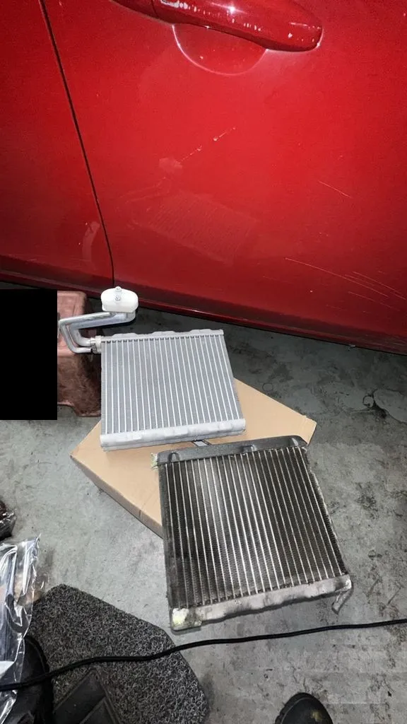 Old darkened evaporator cooling coil next to a new clean coil from a Volvo V60 aircon repair at our Singapore workshop